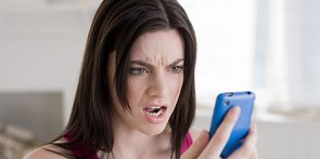 Foto van vrouw die boos kijkt naar mobiele telefoon