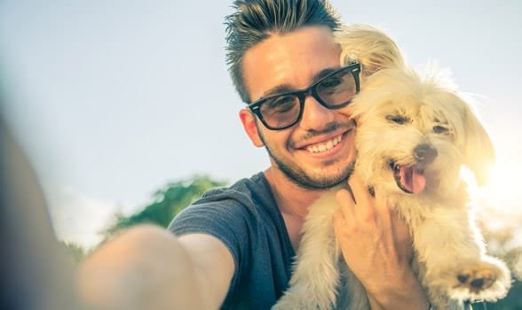 Foto de un hombre tomando un selfie con un perro