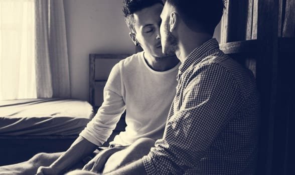 Photo de deux hommes s'embrassant au lit