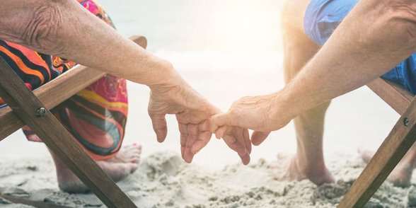Foto eines Paares, das Händchen am Strand hält