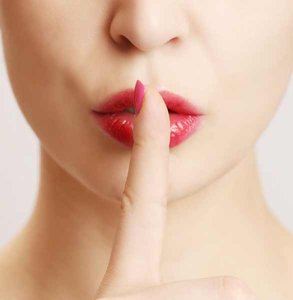 Foto van een vrouw die een vinger op haar lippen houdt