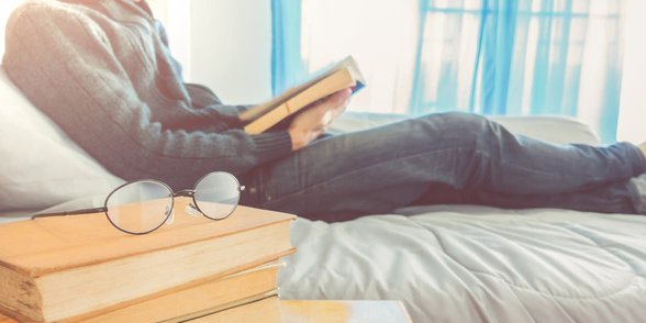 Yatakta kitap okuyan bir adamın fotoğrafı