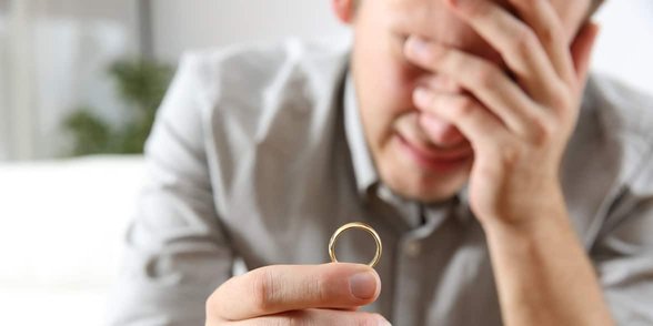 Foto de un hombre llorando con un anillo de bodas